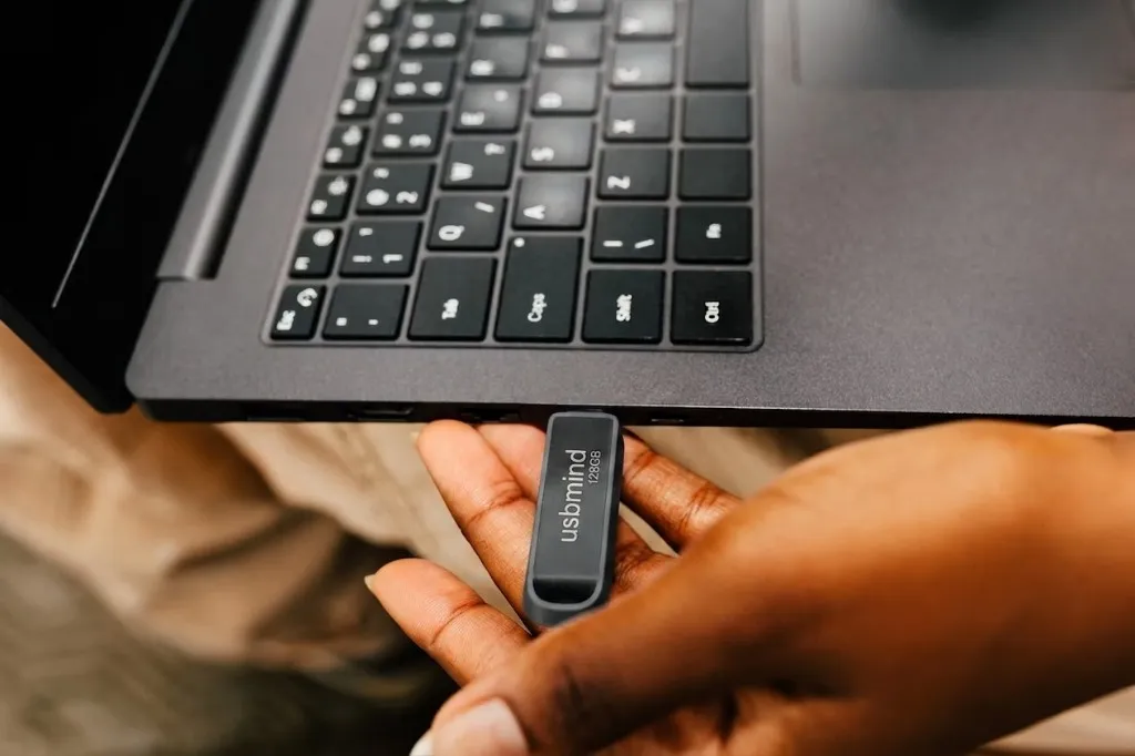 A hand plugging a USBMind flash drive into a laptop